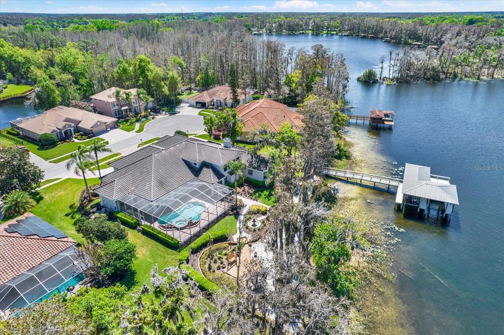 An aerial view shows a waterfront house with a pool, screened lanai, and private dock — 5643 WHITE IBIS LANE, LAND O LAKES, FL