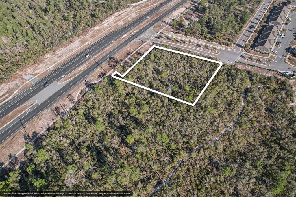 An aerial view shows a rectangular plot of land outlined in white near a highway — 6414 COMMERCIAL WAY, WEEKI WACHEE, FL
