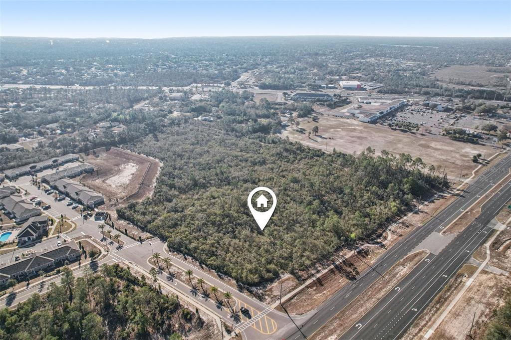 An aerial view shows a wooded plot of land marked with a house icon — 6414 COMMERCIAL WAY, WEEKI WACHEE, FL