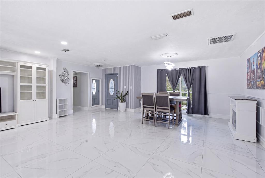 A dining area with a grey front door, striped wallpaper, and white marble-look tile flooring — 1124 KING ARTHUR COURT, VALRICO, FL