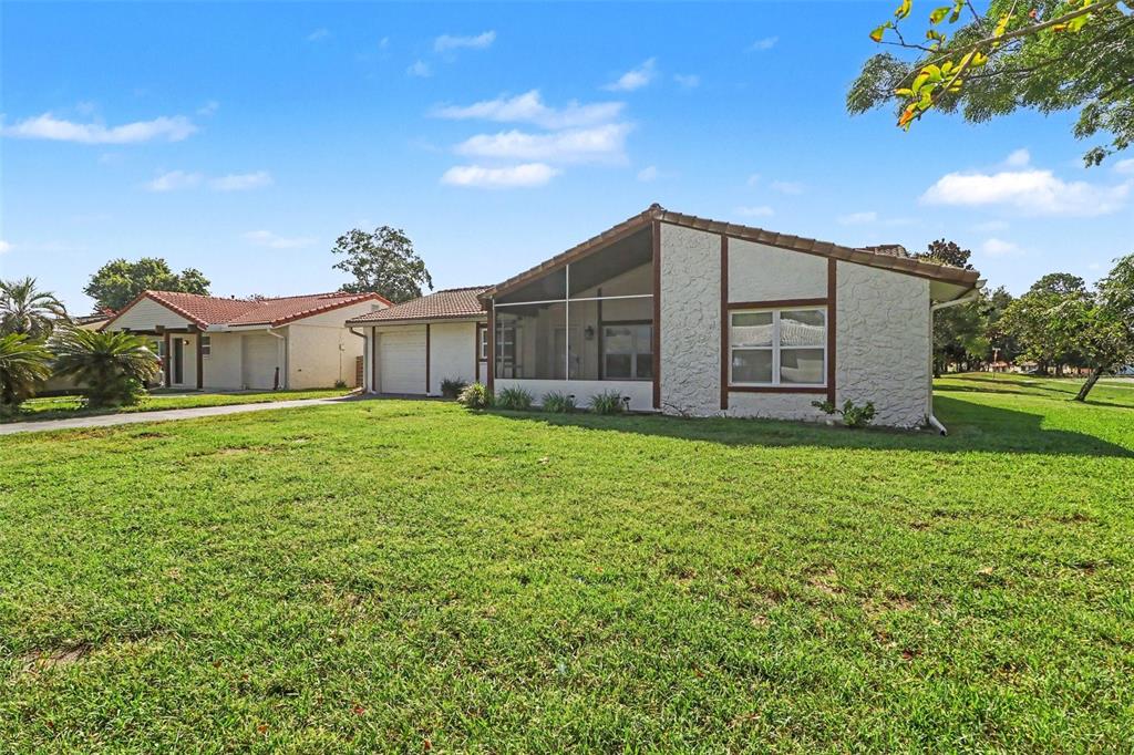 A single-story house with a white textured exterior, a screened-in porch, and a large lawn — 10157 BLUFF COURT, ORLANDO, FL