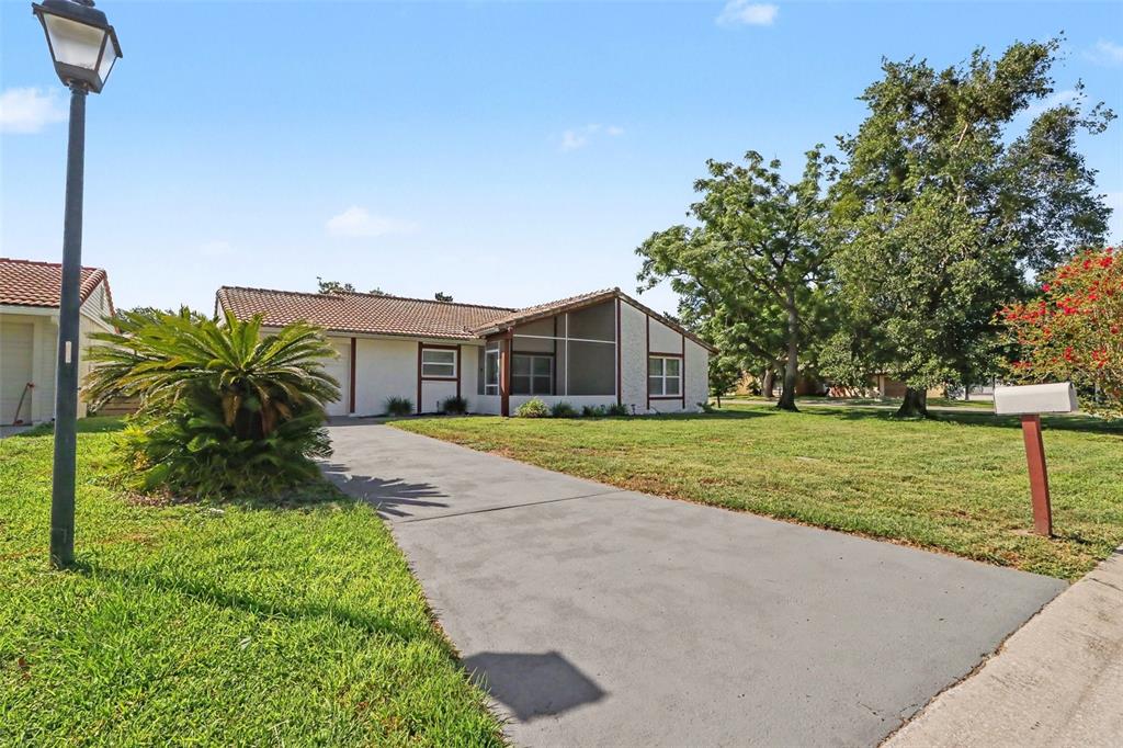 A single-story house with a tiled roof, screened porch, and concrete driveway sits on grass — 10157 BLUFF COURT, ORLANDO, FL
