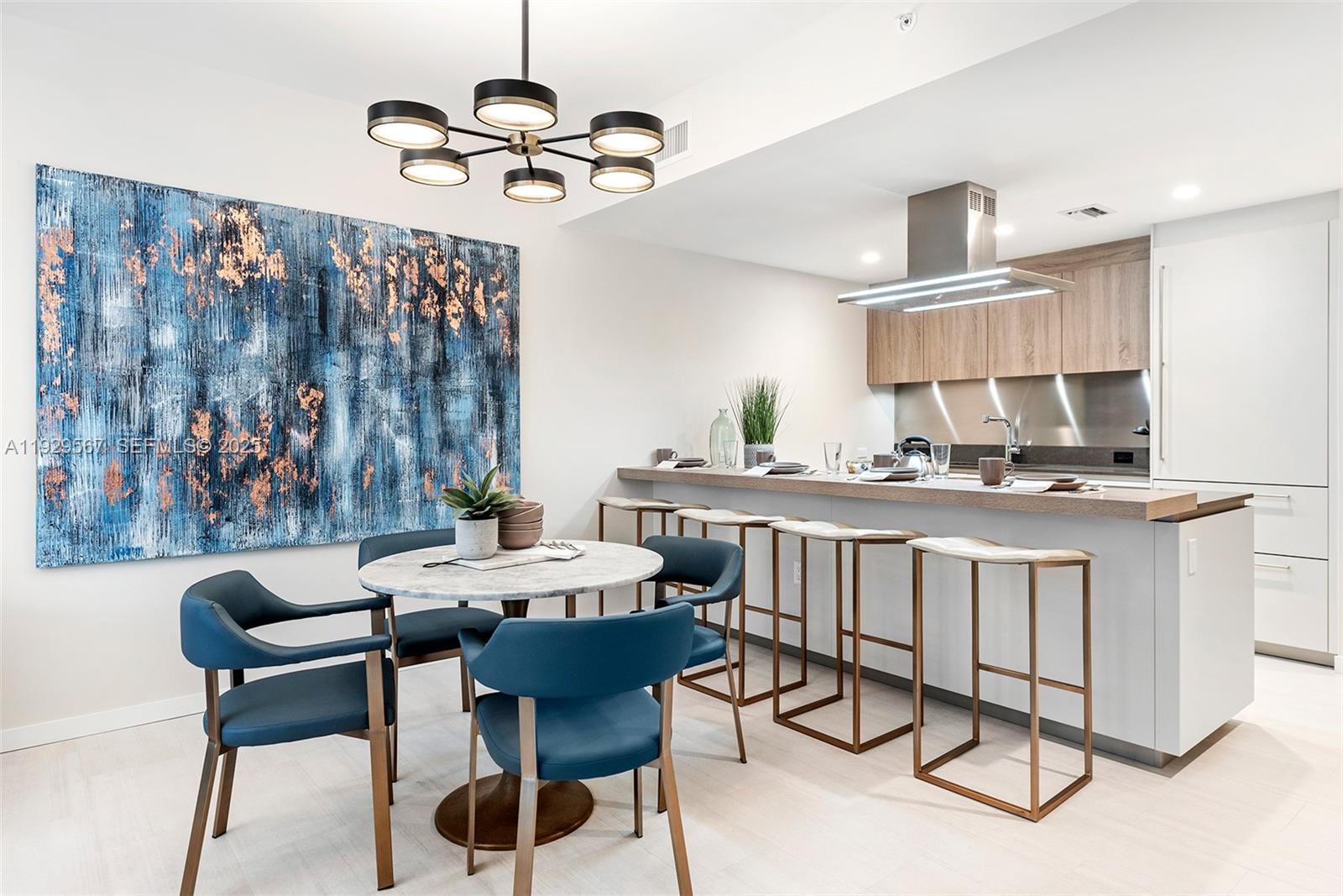 A dining area with a round marble table and blue chairs sits beside a kitchen island — 1000 Brickell Plz # 4005, Miami FL 33131, MIAMI, FL