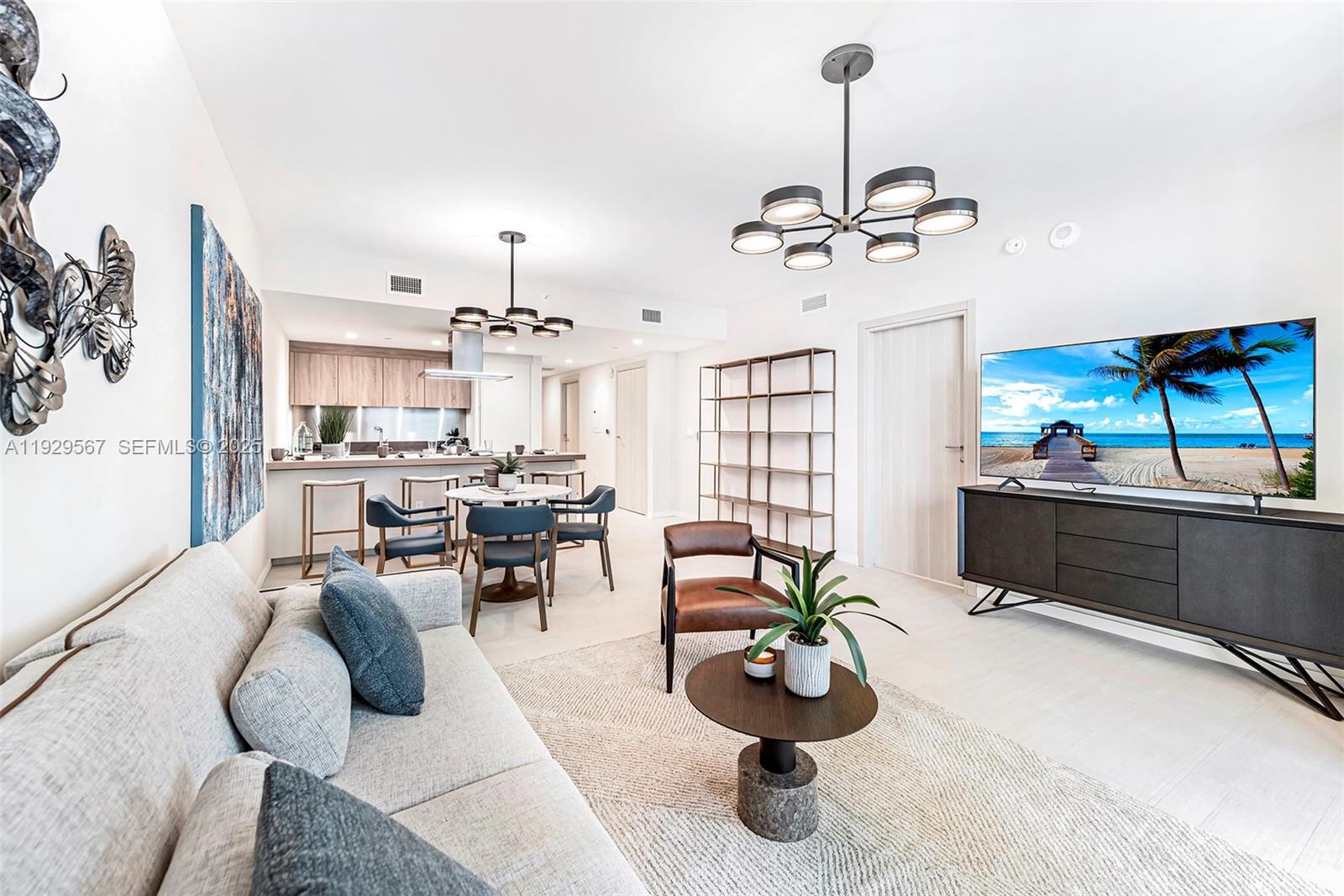 An open-concept living and dining area features a modern kitchen, light flooring, and contemporary lighting — 1000 Brickell Plz # 4005, Miami FL 33131, MIAMI, FL