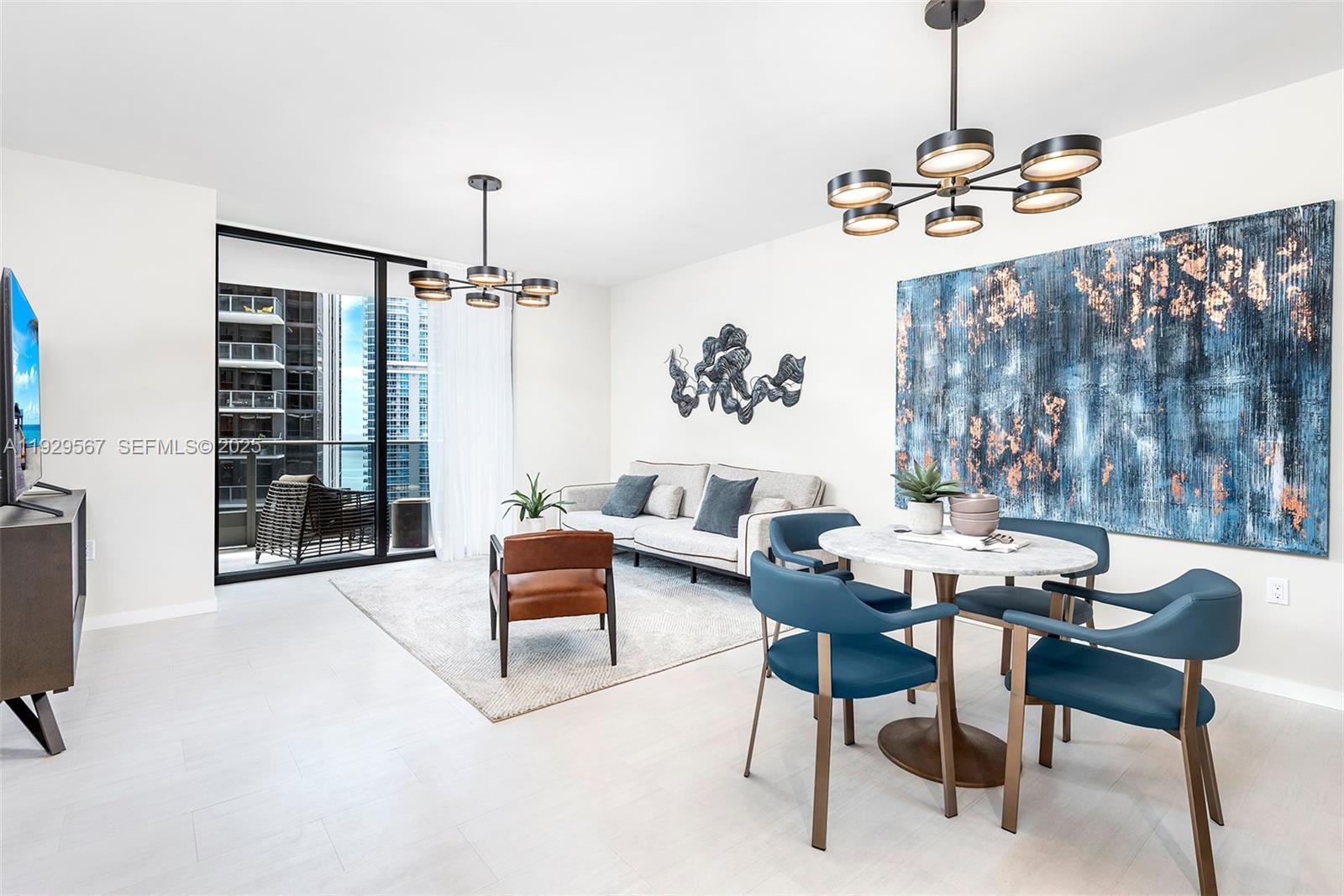 A modern living and dining area features white tile floors, blue accent furniture, and chandeliers — 1000 Brickell Plz # 4005, Miami FL 33131, MIAMI, FL