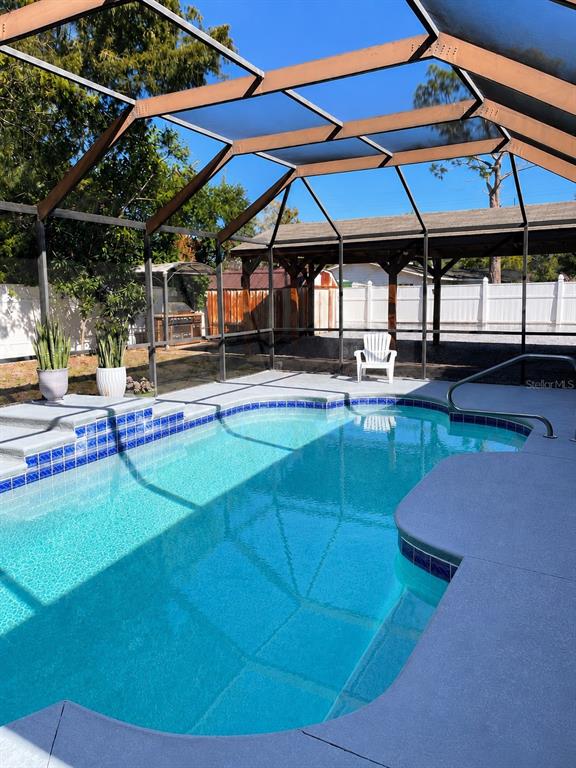 A swimming pool with a screened-in enclosure and a covered patio area in the background — 490 WATER ROAD, OCALA, FL