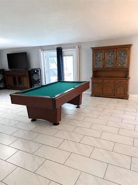 A game room features a pool table, a wooden hutch, and a television on tile flooring — 490 WATER ROAD, OCALA, FL