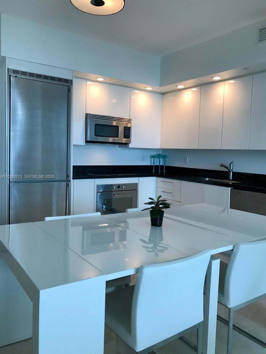 A modern kitchen features white cabinets, stainless steel appliances, and a black countertop — 92 SW 3rd St # 3712, Miami FL 33130, MIAMI, FL