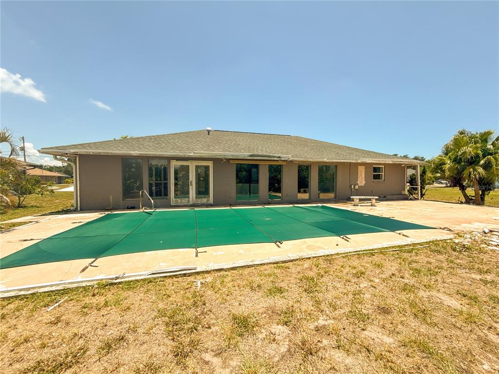 The rear exterior of a house features a covered swimming pool and a concrete patio — 132 MARK TWAIN LANE, ROTONDA WEST, FL