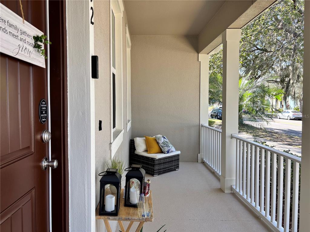A covered front porch features a wicker chair, two lanterns on a table, and railings — 13712 SUMMERPORT VILLAGE PARKWAY, WINDERMERE, FL