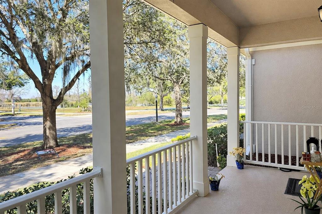 A covered front porch with white railings overlooks a street lined with trees — 13712 SUMMERPORT VILLAGE PARKWAY, WINDERMERE, FL