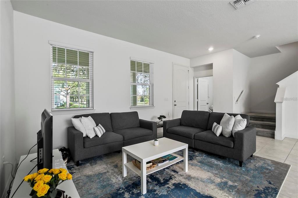 A living room features two dark gray sofas, a white coffee table, and a blue rug — 13712 SUMMERPORT VILLAGE PARKWAY, WINDERMERE, FL
