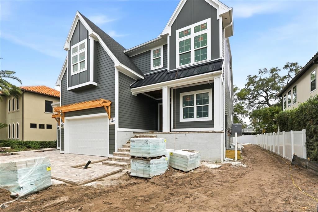 The exterior of a two-story gray house under construction with a paved driveway and pallets — 4307 W SEVILLA STREET, TAMPA, FL