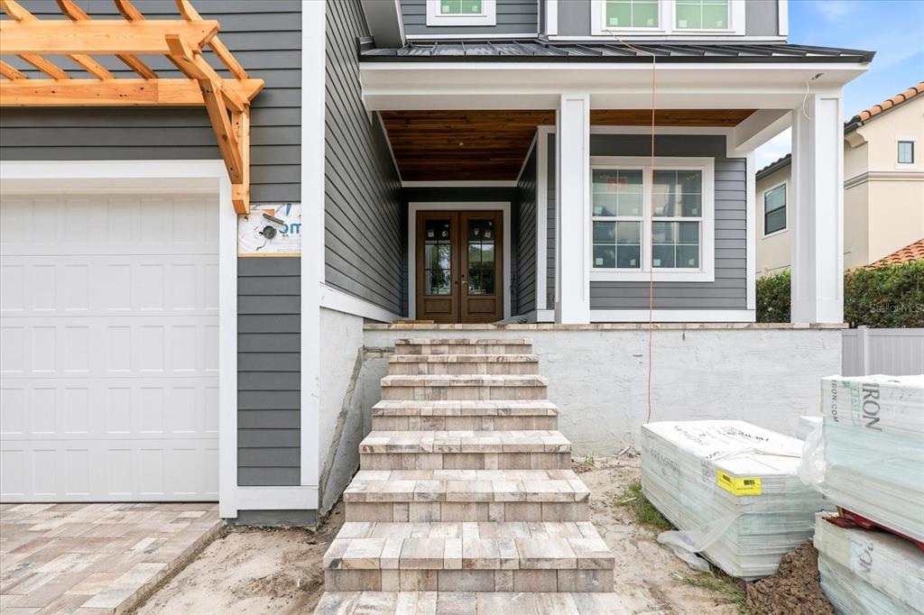 A gray house exterior features a stone staircase leading to a wooden double front door — 4307 W SEVILLA STREET, TAMPA, FL