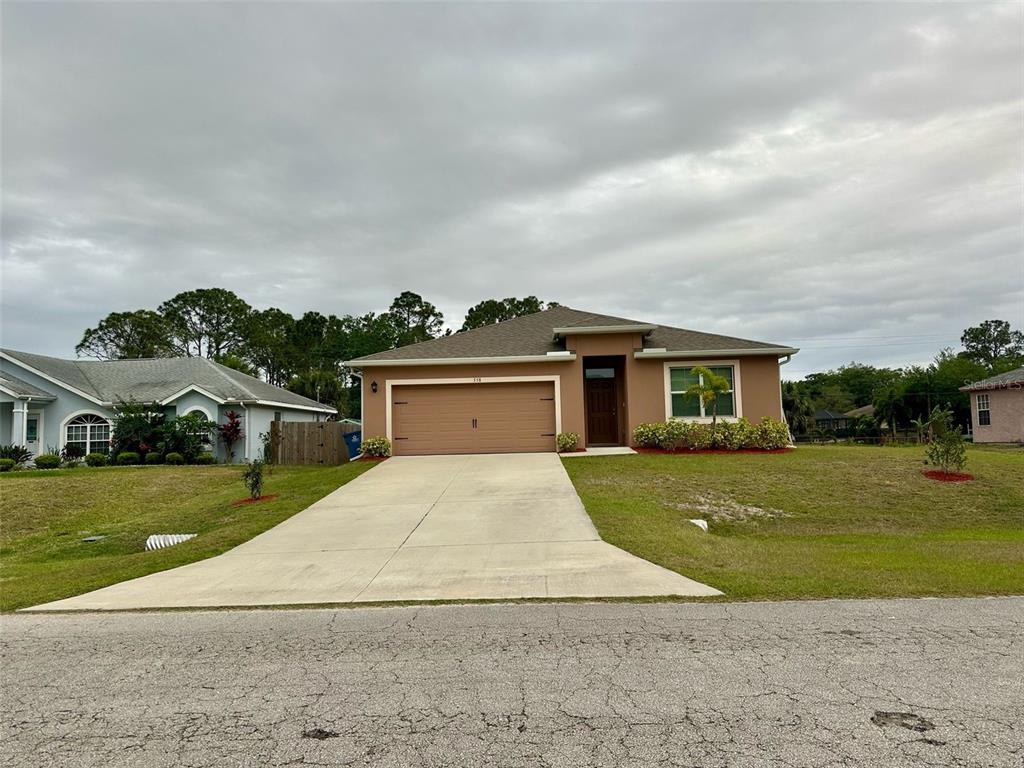A single-story house with a tan stucco exterior, a two-car garage, and a concrete driveway — 538 VIN ROSE CIRCLE SE, PALM BAY, FL