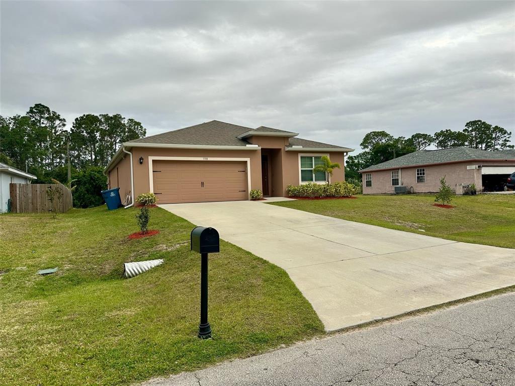 A tan single-story house with a two-car garage and a concrete driveway — 538 VIN ROSE CIRCLE SE, PALM BAY, FL