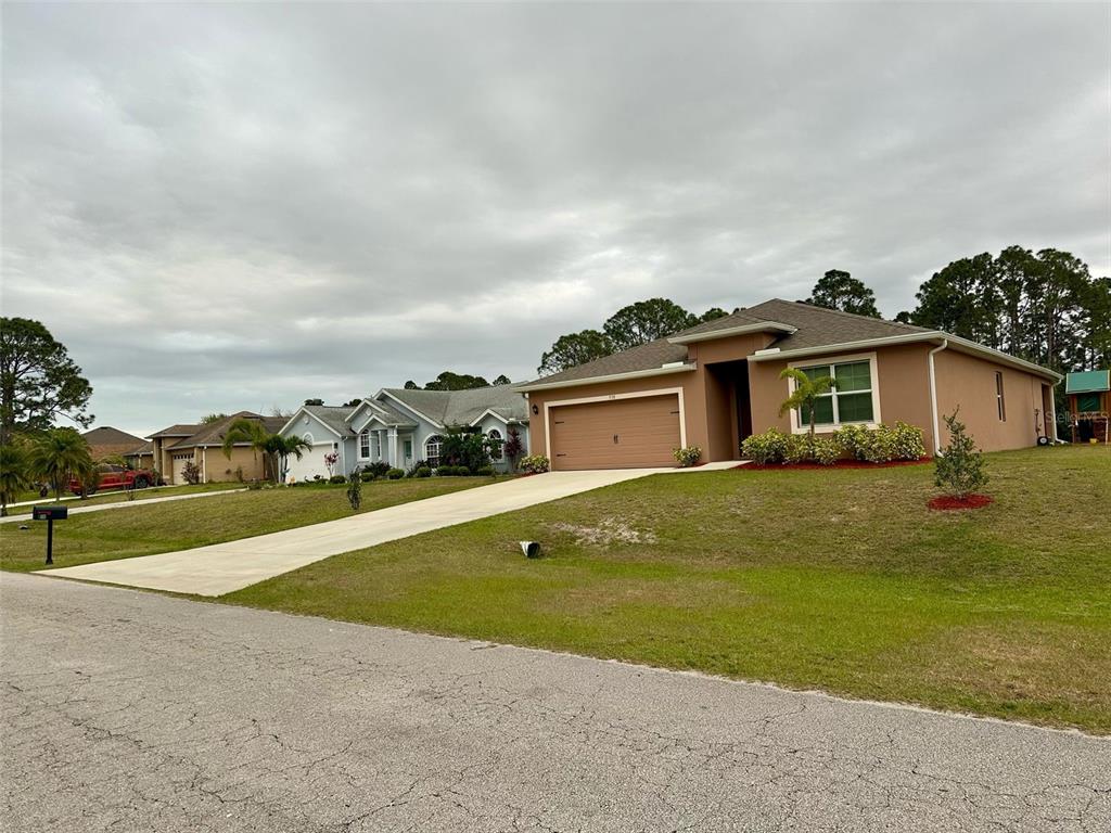 A tan single-story house with a two-car garage and a concrete driveway — 538 VIN ROSE CIRCLE SE, PALM BAY, FL