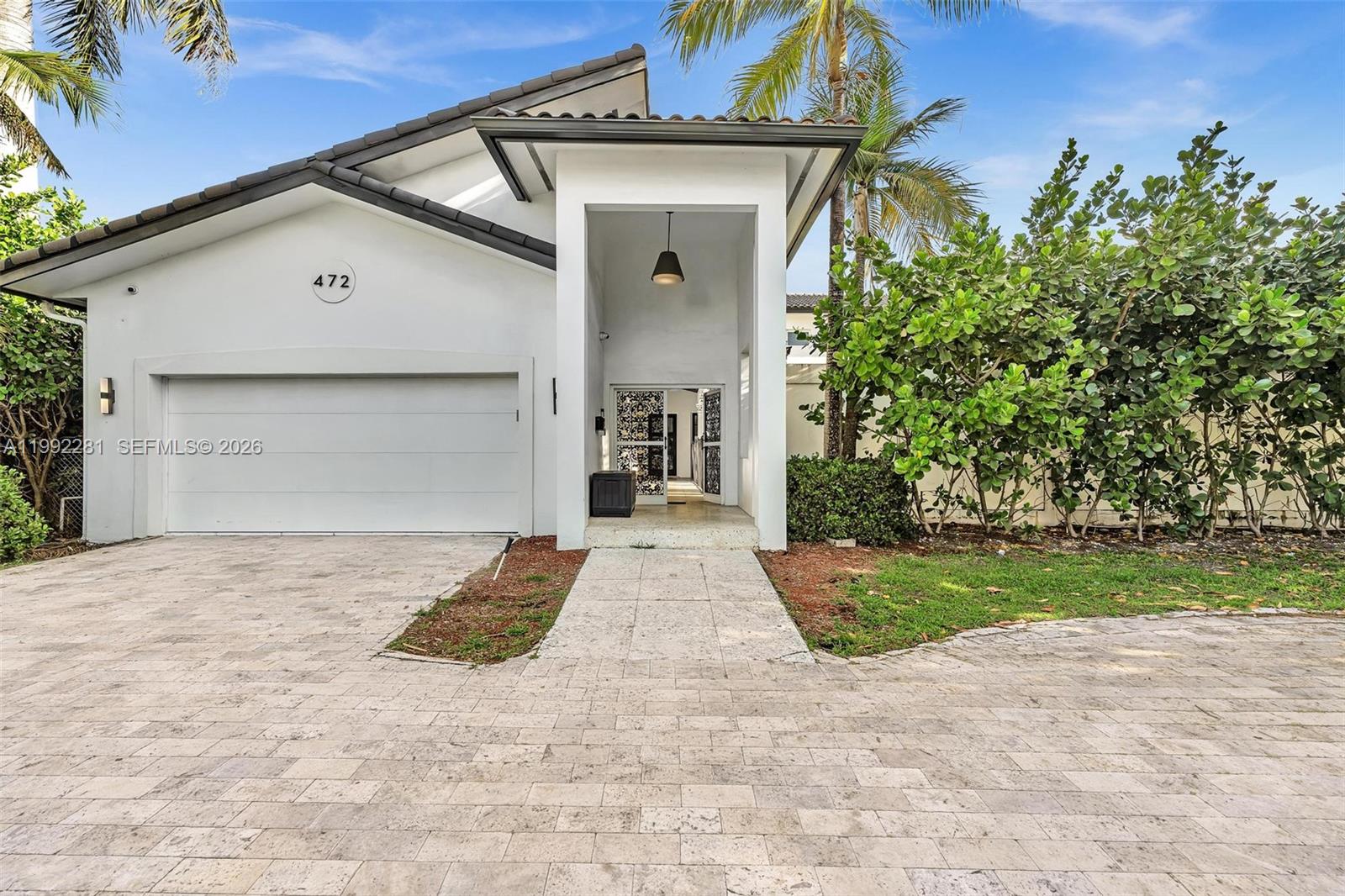 A white house exterior features a paved driveway, a garage, and a covered entryway — 472 Sunset Dr, Hallandale Beach FL 33009, HALLANDALE BEACH, FL