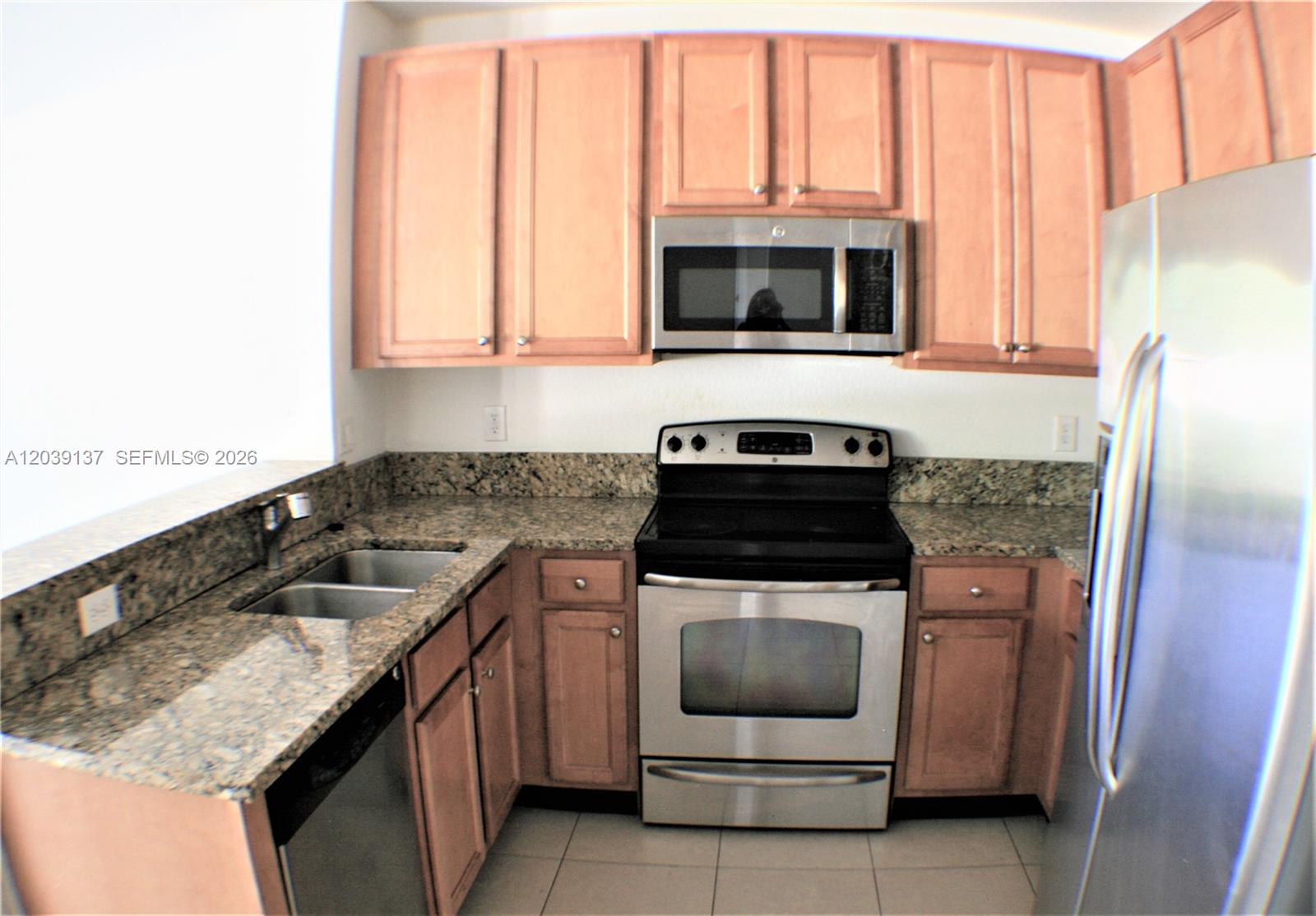 A kitchen features light wood cabinets, granite countertops, and stainless steel appliances — 202 Las Brisas Cir, Sunrise FL 33326, SUNRISE, FL