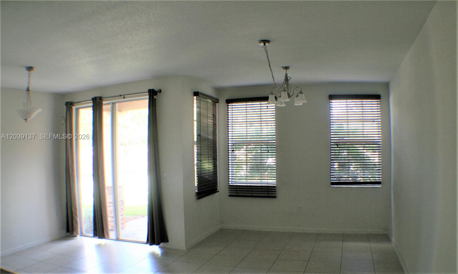 A dining area features tile flooring, a chandelier, sliding glass doors, and three windows — 202 Las Brisas Cir, Sunrise FL 33326, SUNRISE, FL