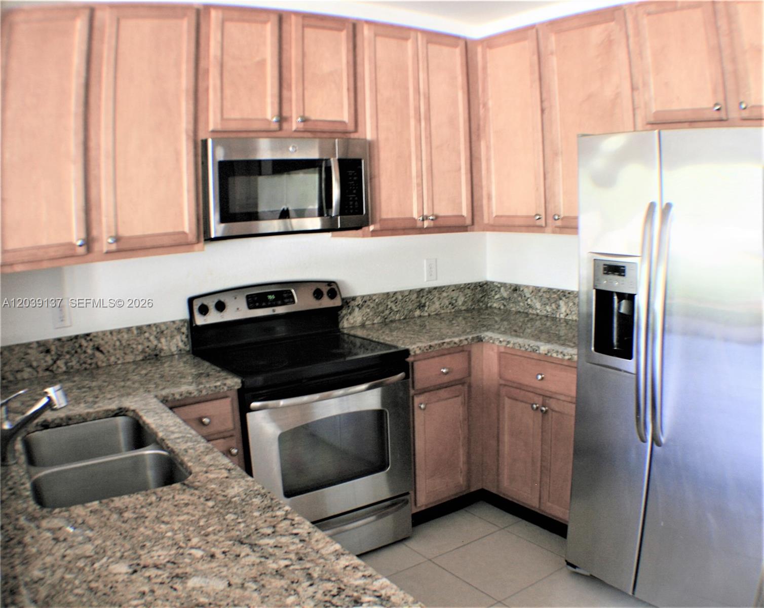 A kitchen features light wood cabinets, granite countertops, and stainless steel appliances — 202 Las Brisas Cir, Sunrise FL 33326, SUNRISE, FL