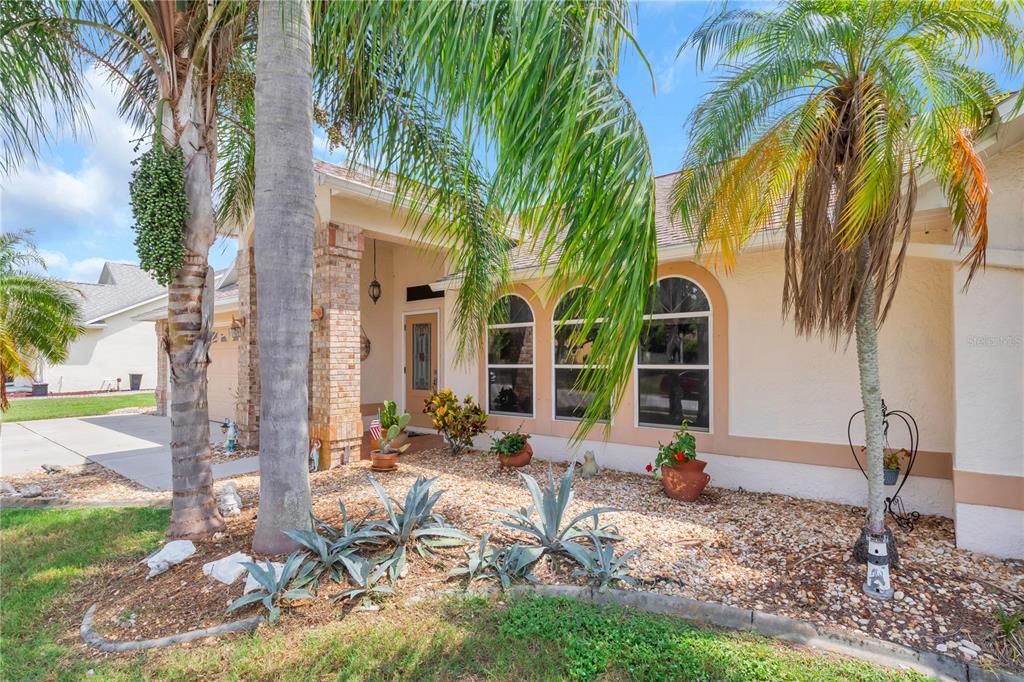 The exterior of a single-story house features a brick-columned entryway, arched windows, and palm trees — 2400 BENT PINE STREET, MELBOURNE, FL