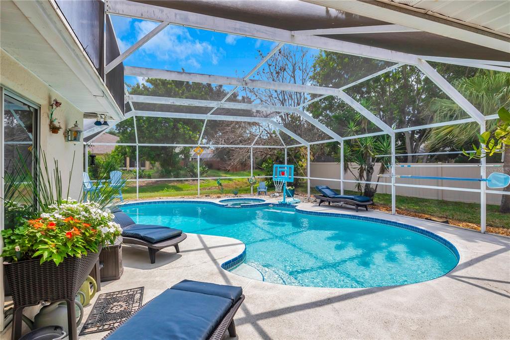 A screened-in pool area features a swimming pool, a hot tub, and lounge chairs — 2400 BENT PINE STREET, MELBOURNE, FL