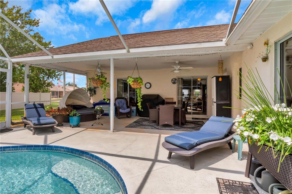 A covered patio features a swimming pool, lounge chairs, and outdoor dining furniture — 2400 BENT PINE STREET, MELBOURNE, FL