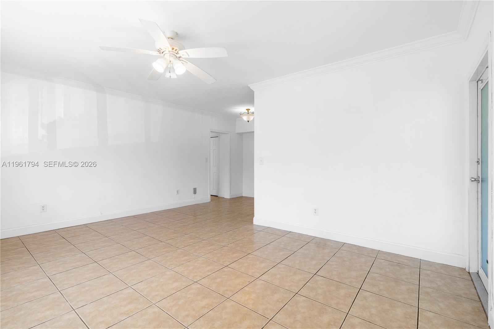 An empty room features white walls, tan tile flooring, and a ceiling fan — 315 69th St # 112, Miami Beach FL 33141, MIAMI BEACH, FL