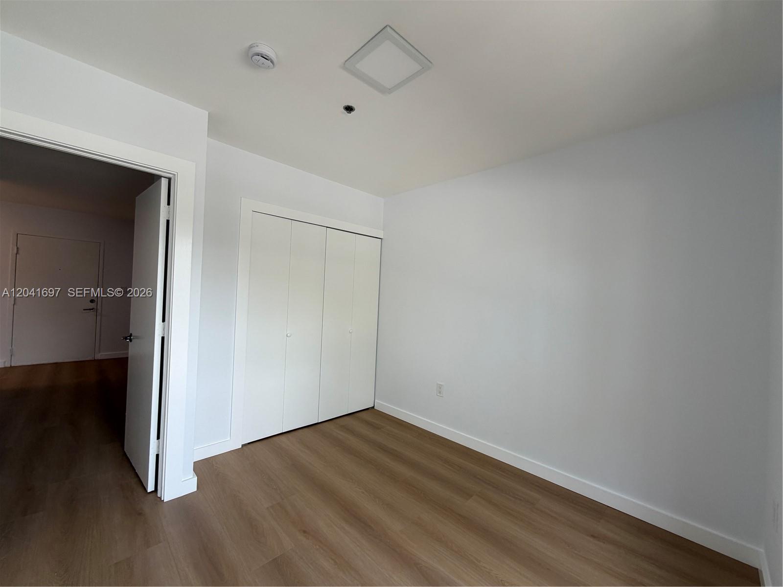 A bedroom features white walls, light wood-look flooring, and a white bi-fold closet door — 717 SW 11th Ave # 206, Miami FL 33130, MIAMI, FL