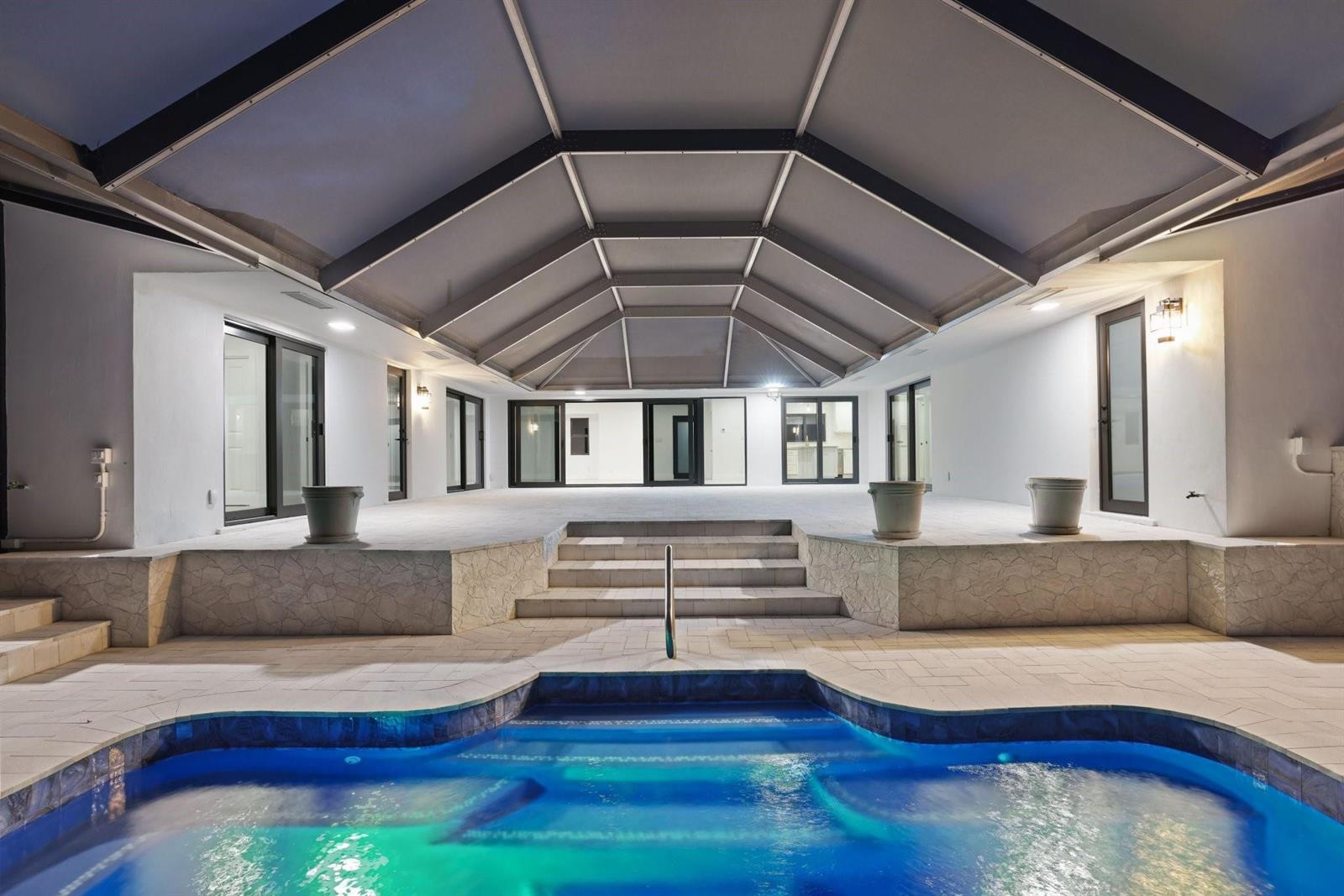A covered patio with stone steps leads to a swimming pool at night — 550 SW 6th Avenue, Boca Raton FL 33486, BOCA RATON, FL