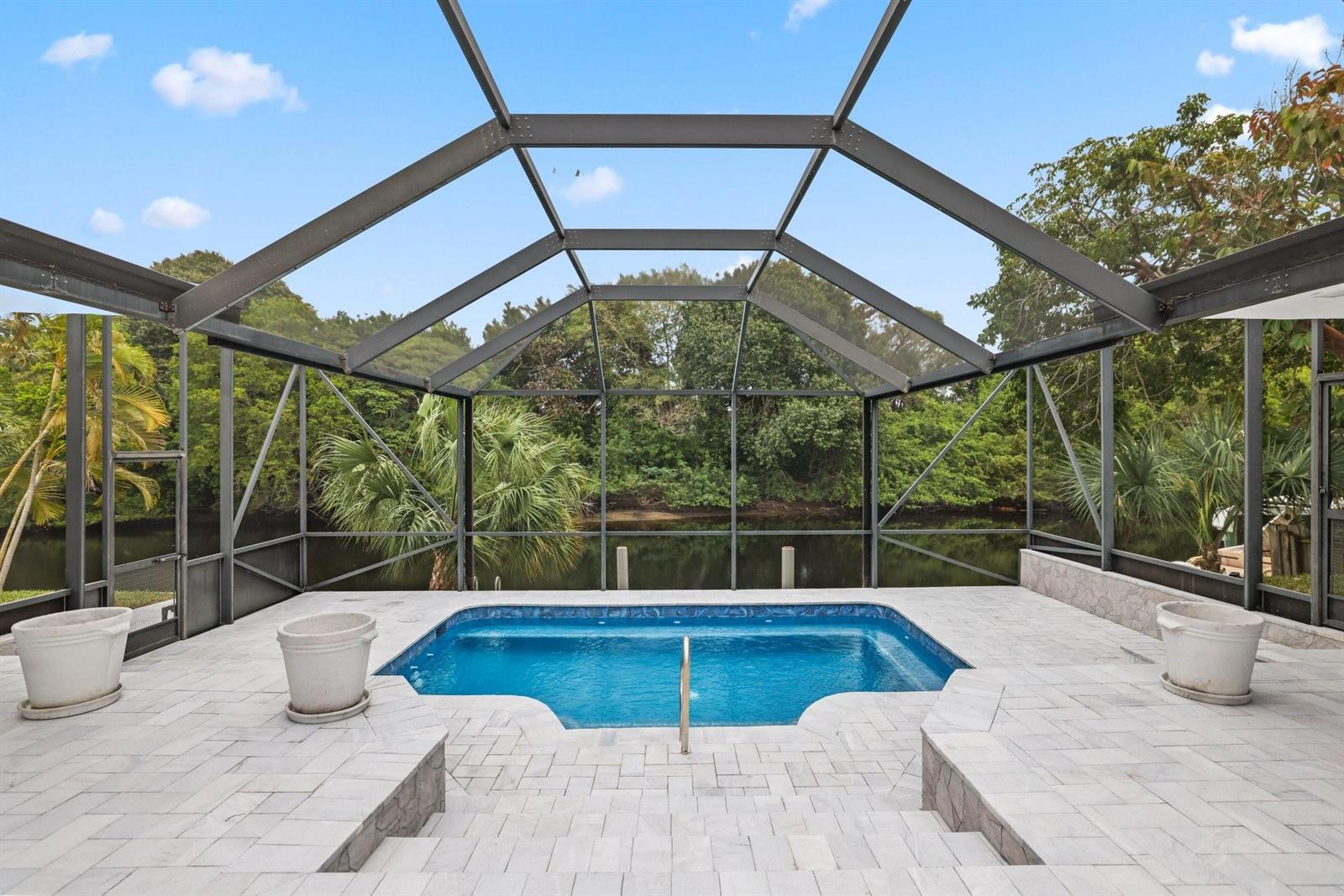 A rectangular swimming pool sits on a paved patio enclosed by a dark metal screen — 550 SW 6th Avenue, Boca Raton FL 33486, BOCA RATON, FL