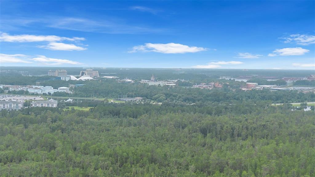 An aerial view shows a suburban neighborhood with houses, a pond, and surrounding forest — 9247 LEGADO DRIVE, WINTER GARDEN, FL
