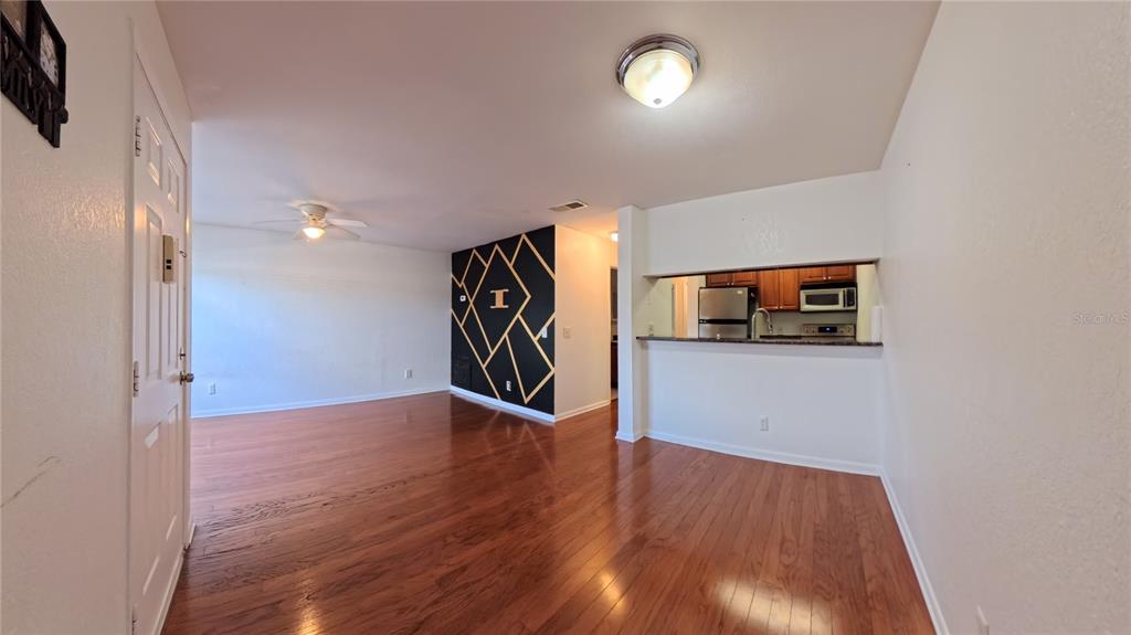 An open-concept living area features hardwood floors, a black accent wall, and a kitchen pass-through — 5440 S MACDILL AVENUE UNIT 1I, TAMPA, FL