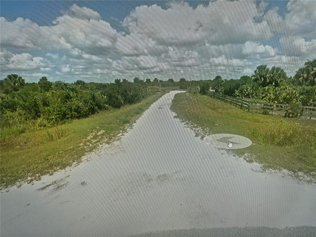 A dirt road stretches through a rural landscape with green vegetation and a wooden fence — 19631 NW 270TH STREET, OKEECHOBEE, FL