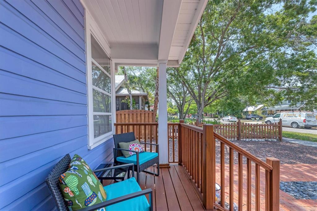 A blue-sided house features a wooden porch with two chairs and a brick walkway — 1676 OAK STREET, SARASOTA, FL