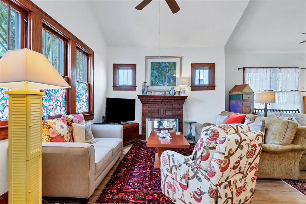 A living room features a brick fireplace, patterned area rug, and colorful upholstered furniture — 1676 OAK STREET, SARASOTA, FL