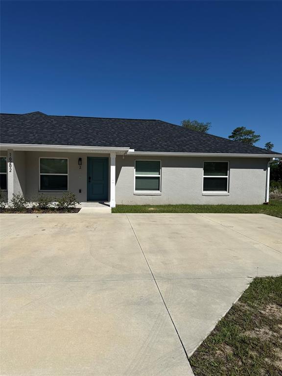 A single-story house with a gray stucco exterior, dark shingled roof, and a concrete driveway — 16292 SW 30TH TERRACE UNIT 2, OCALA, FL