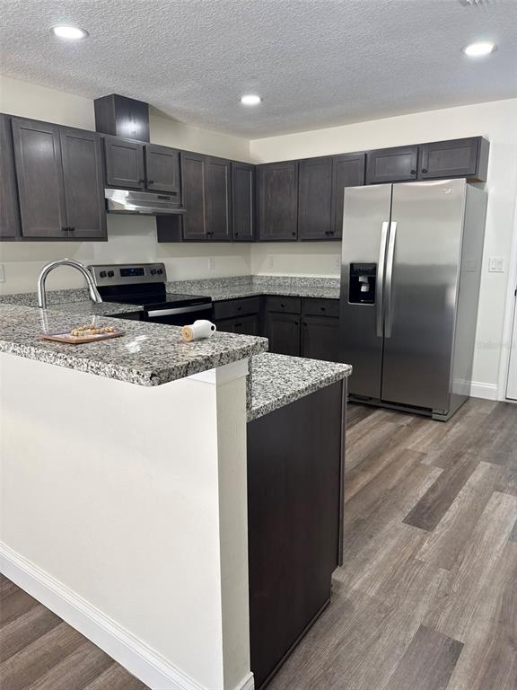 A kitchen features dark wood cabinets, granite countertops, stainless steel appliances, and wood-look flooring — 16292 SW 30TH TERRACE UNIT 2, OCALA, FL