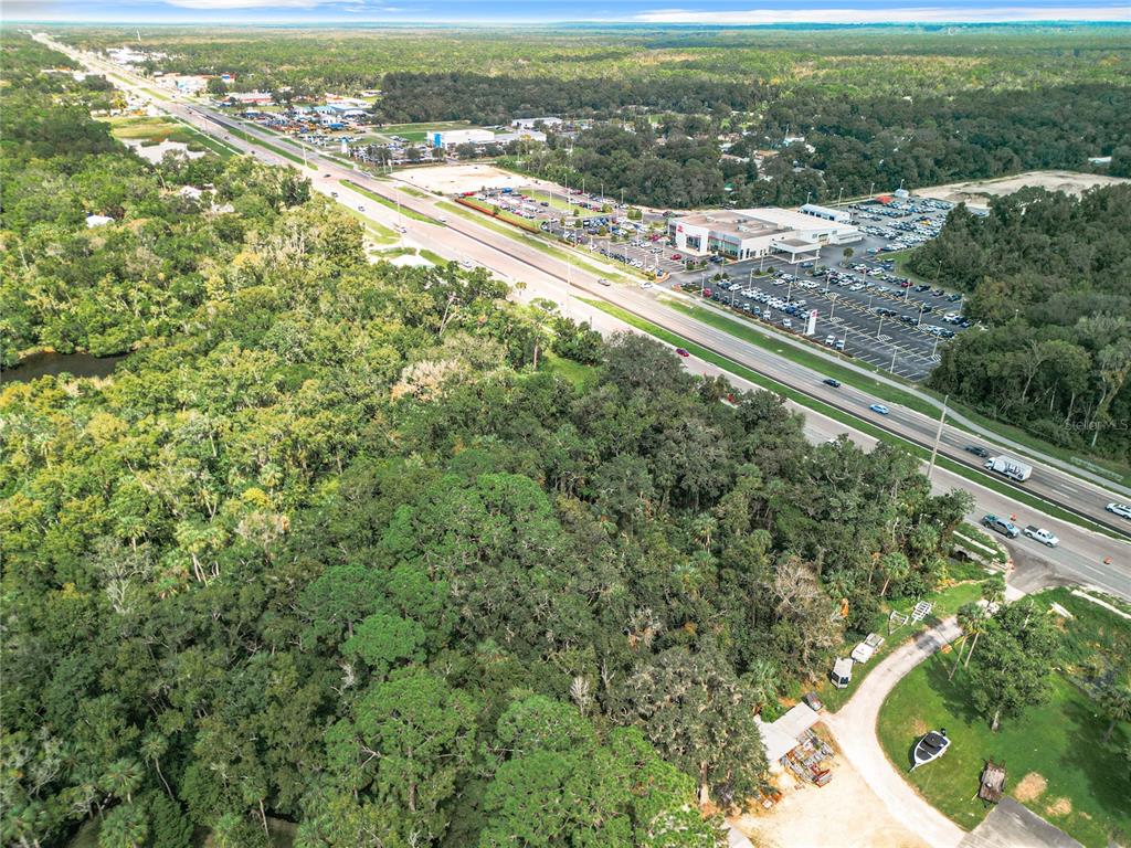 An aerial view shows a wooded lot adjacent to a highway and a commercial parking lot — 2520 S SUNCOAST BOULEVARD, HOMOSASSA, FL