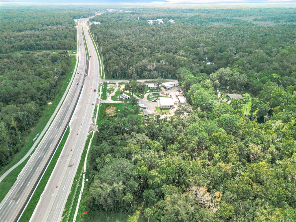 An aerial view shows a multi-lane highway running alongside a wooded property with several buildings — 2520 S SUNCOAST BOULEVARD, HOMOSASSA, FL