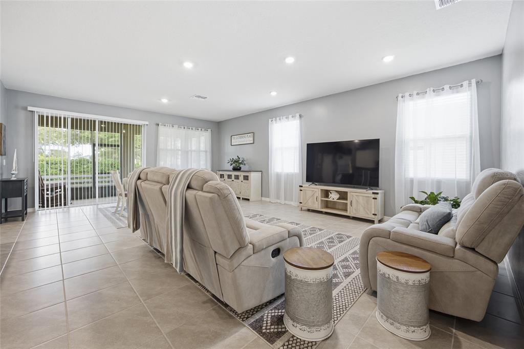 A living room features light gray walls, tile flooring, a television, and two reclining sofas — 9309 SW 60TH COURT ROAD, OCALA, FL