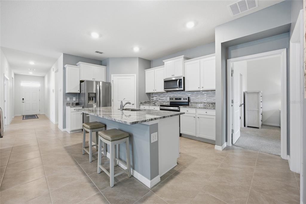 A kitchen with white cabinets, granite countertops, a center island, and light-colored tile flooring — 9309 SW 60TH COURT ROAD, OCALA, FL
