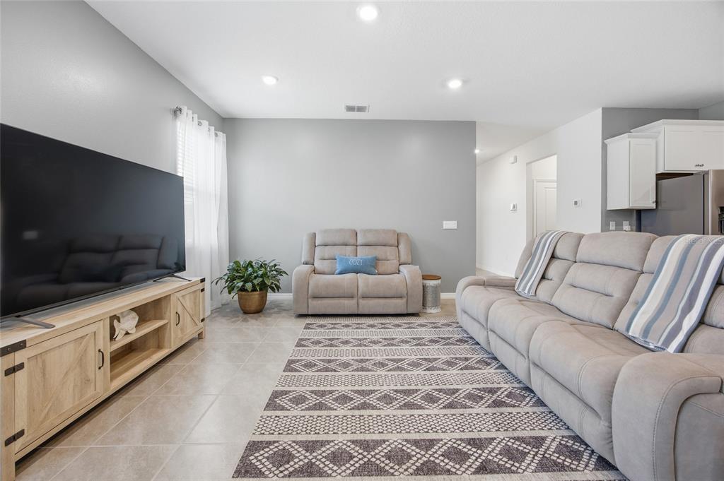 A living room features a large television, light gray sofa and armchair, and patterned area rug — 9309 SW 60TH COURT ROAD, OCALA, FL