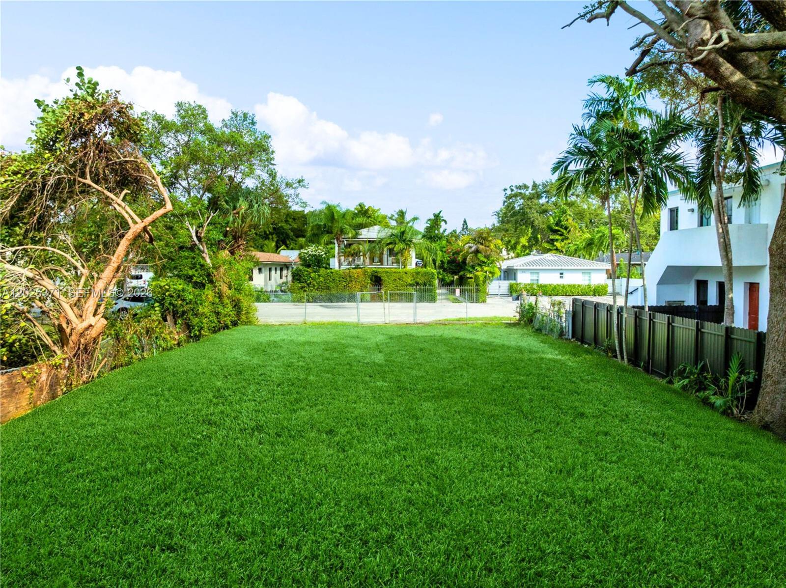 A large, flat, grassy backyard is enclosed by a fence and surrounded by mature trees — 508 NE 67th St, Miami FL 33138, MIAMI, FL