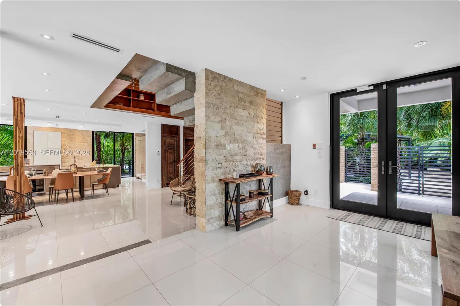 A bright, modern entryway features a stone accent wall, tile floors, and a staircase — 994-990 NE 78th, Miami FL 33138, MIAMI, FL