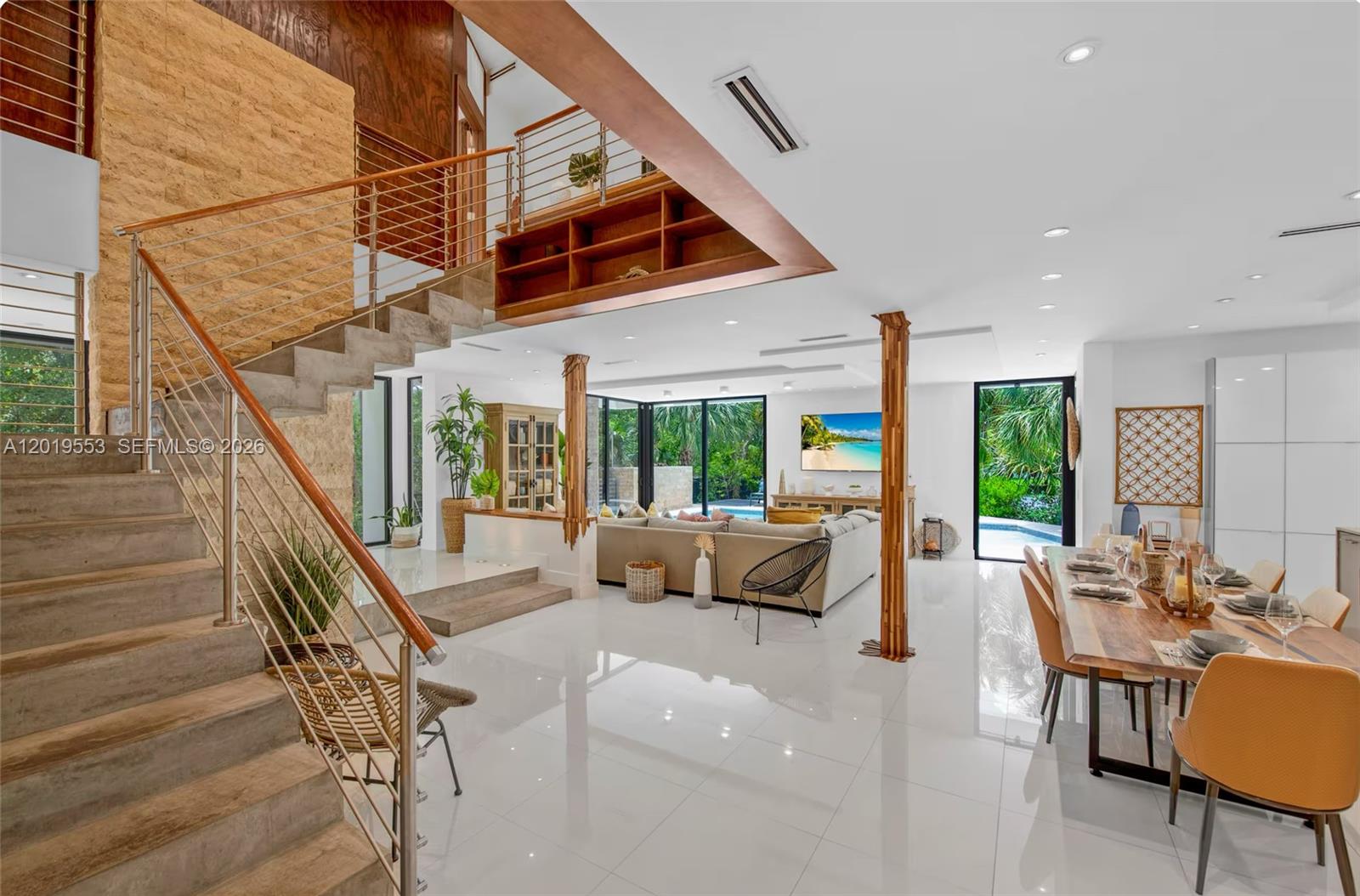 An open-concept living and dining area features a floating staircase, stone wall, and tile floors — 994-990 NE 78th, Miami FL 33138, MIAMI, FL
