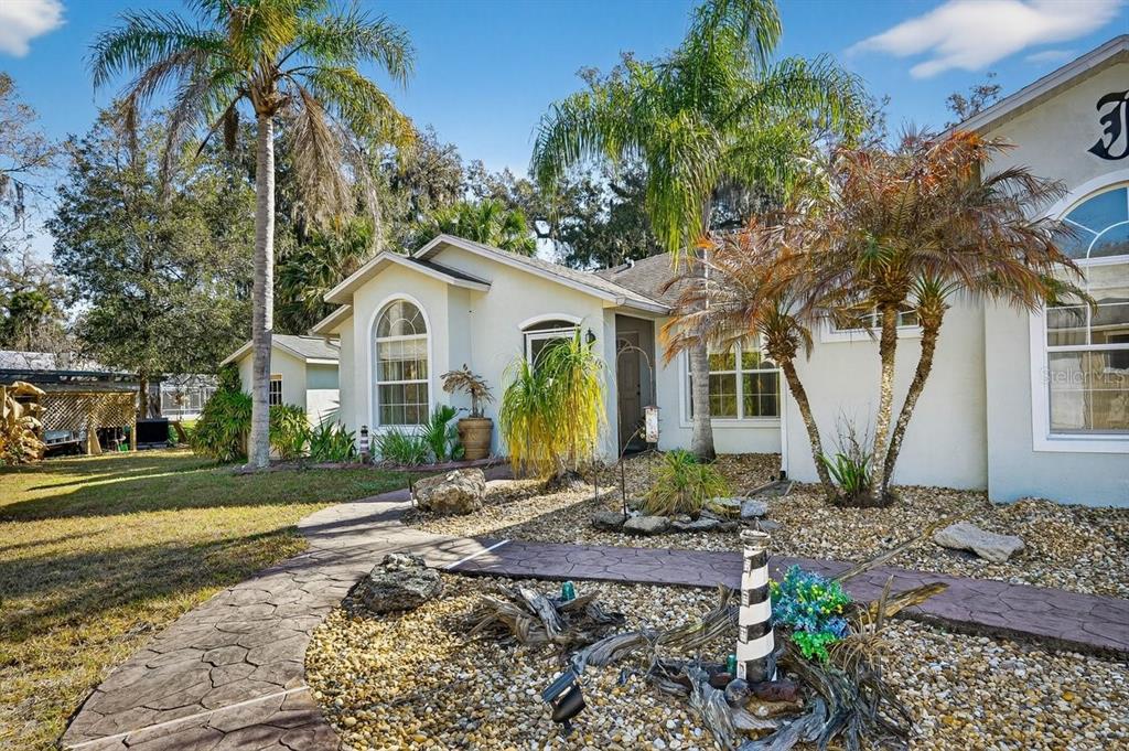 A stone walkway leads to the front entrance of a house with palm trees — 2576 SHILO GLYNN LANE, NEW SMYRNA BEACH, FL