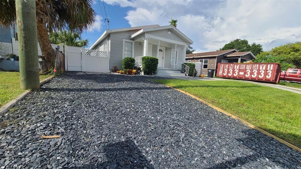 A gray house with a gravel driveway and a red dumpster in the front yard — 2519 W WALNUT, TAMPA, FL