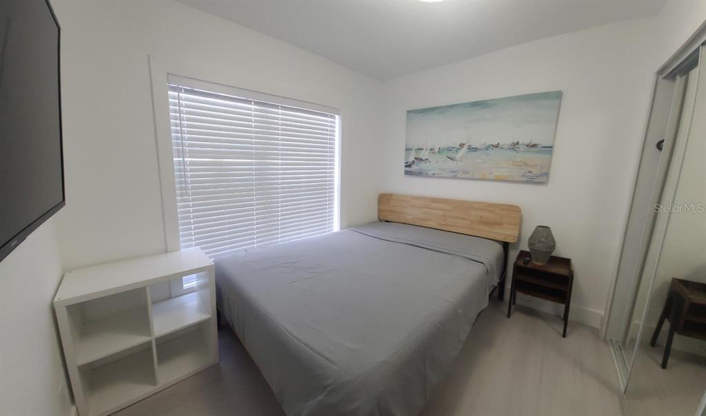 A bedroom features a bed with a wooden headboard, a white bookshelf, and a window — 2519 W WALNUT, TAMPA, FL